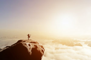 Martial artist training on cliff in sunset