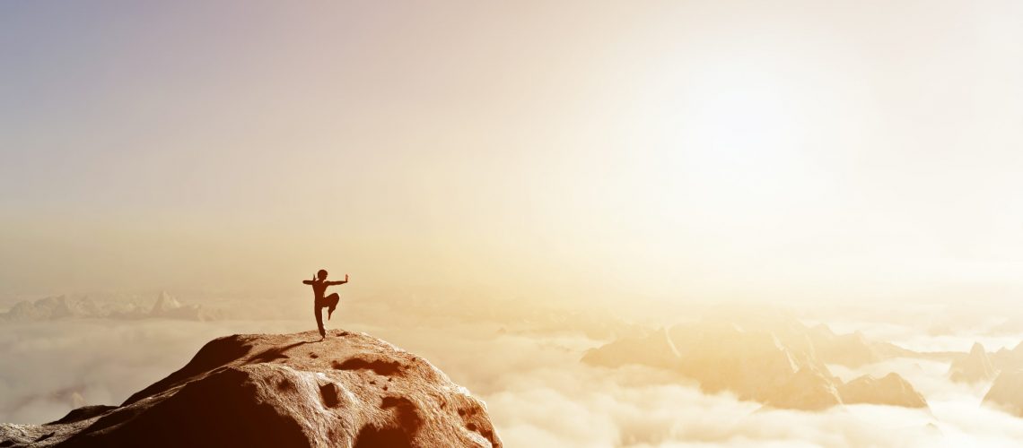 Martial artist training on cliff in sunset